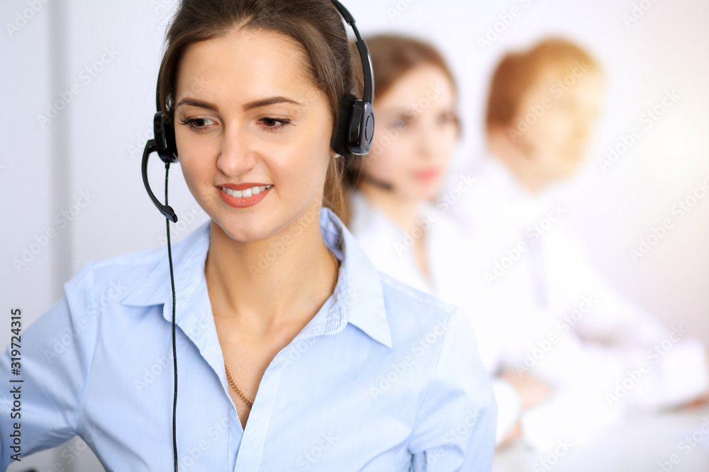 Call center. Focus on beautiful business woman using headset in sunny office Call center. Focus on beautiful business woman using headset in sunny office