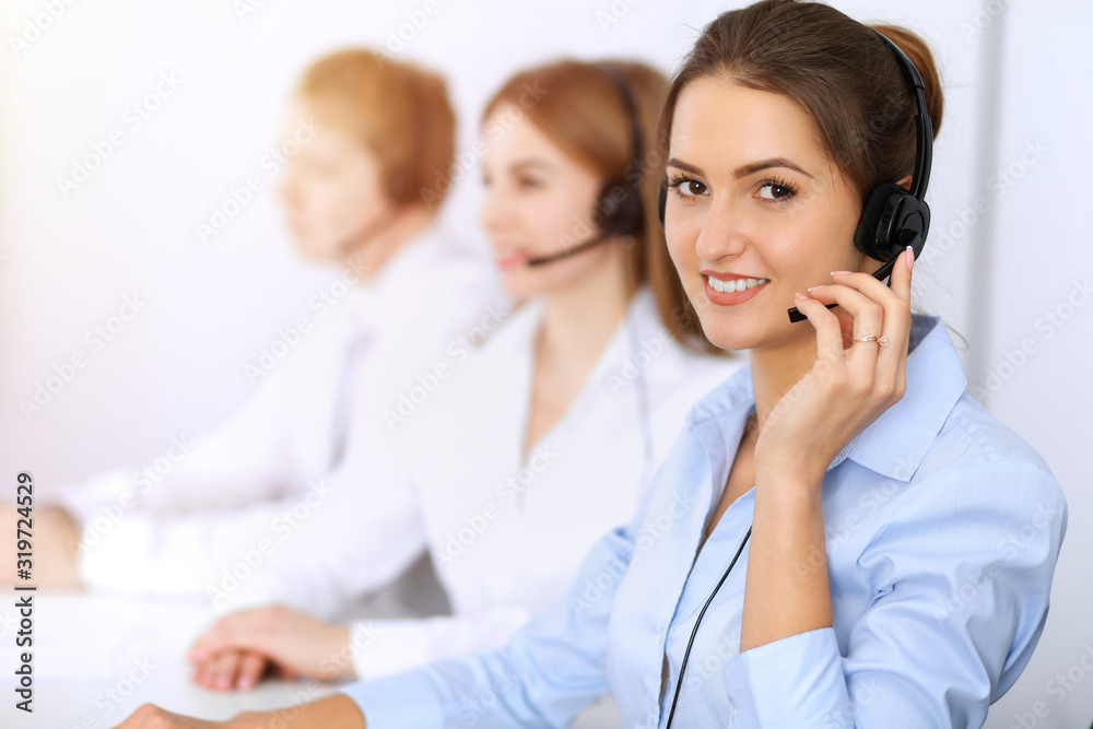 Call center. Focus on beautiful business woman using headset in sunny office Call center. Focus on beautiful business woman using headset in sunny office