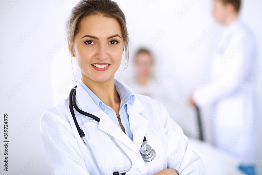 Female doctor smiling on the background with patient in the bed and two doctors Female doctor smiling on the background with patient in the bed and two doctors