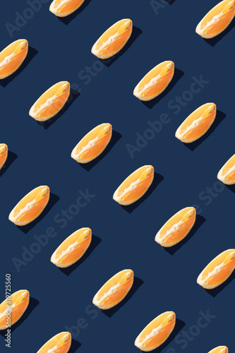 Flat lay pattern with summer orange fruit on blue background. Minimal concept with sharp shadows. Trendy social mockup or wallpaper.