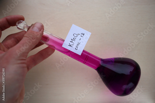 Mixing a purple aqueous solution of potassium permanganate in a flask by hand. photo