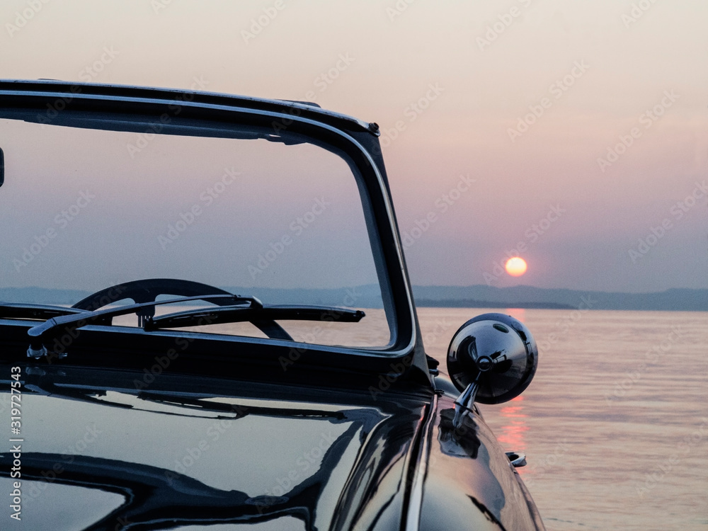 Vintage car near lake at sunset