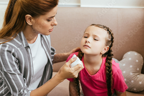 worried mother holding napkin near daughter with nasal bleeding