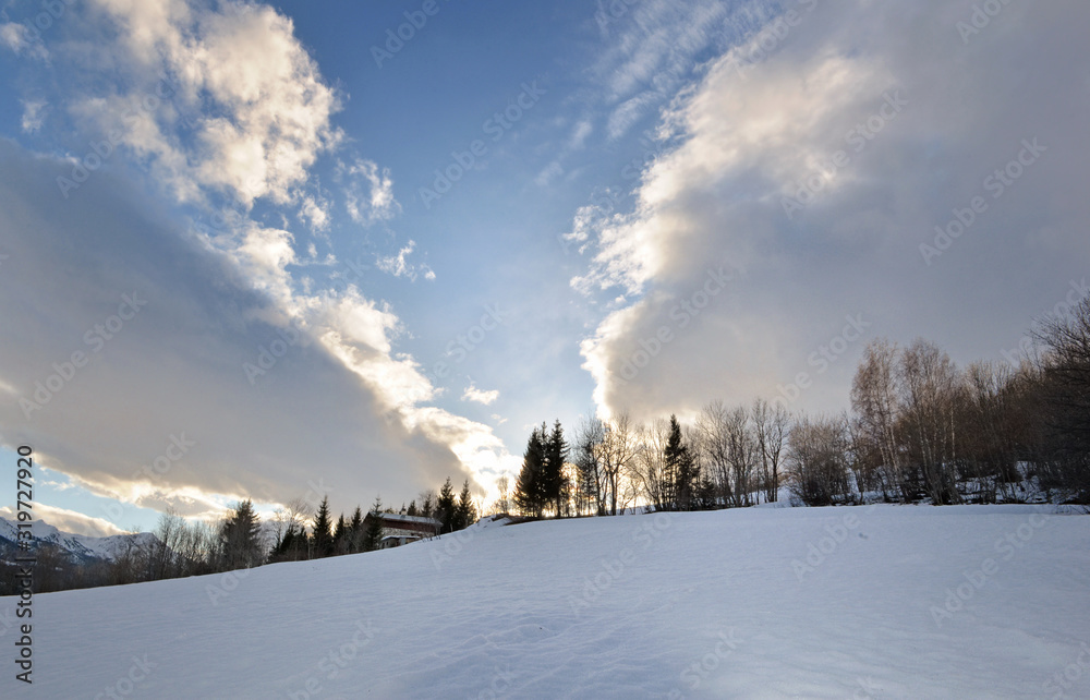 beautiful landscape of  mountain covered with snow  with cloudy sky and sunlight in the trees