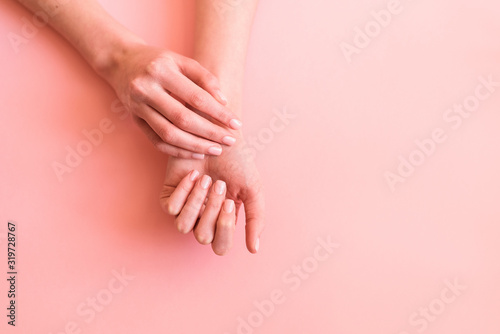 hands with neat manicure on a pink background © Irina