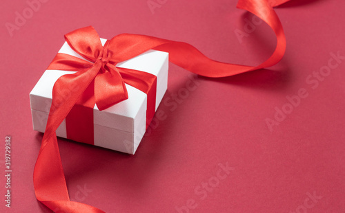 White gift box with red ribbon on red background. side view. Holiday time at any time of the year