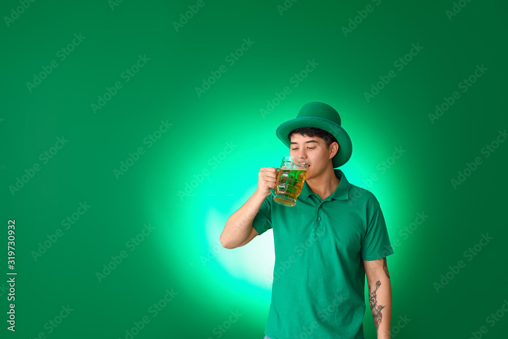 Young Asian man with beer on color background. St. Patrick's Day celebration Young Asian man with beer on color background. St. Patrick's Day celebration