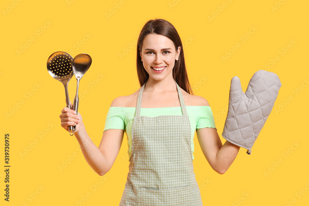 Young housewife with kitchenware on color background Young housewife with kitchenware on color background