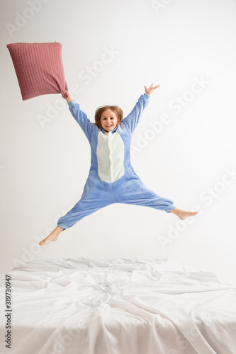 Little girl in soft warm pajama colored bright playing at home. Cute model having fun, party, laughting, playing, looks stylish and happy. Concept of childhood, leisure activity, happiness.
