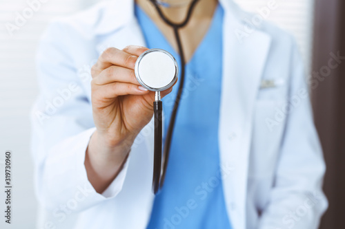 Unknown doctor woman holds stethoscope head, close-up. Physician ready to examine and help patient. Helping and insurance in health care, best treatment and medicine concept