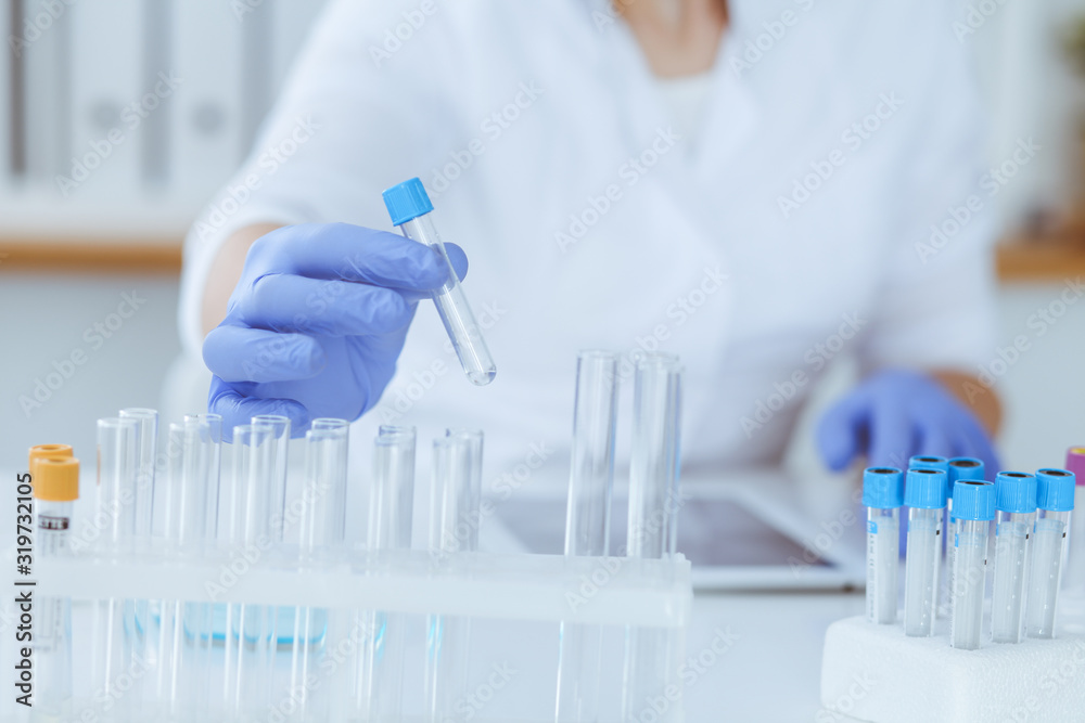 Close-up of professional female scientist in protective eyeglasses making experiment with reagents in laboratory. Medicine and research concept Close-up of professional female scientist in protective eyeglasses making experiment with reagents in laboratory. Medicine and research concept