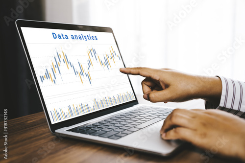 Businessman using a laptop computer with data analytics and statistics information business technology on table top. mockup with clipping path.