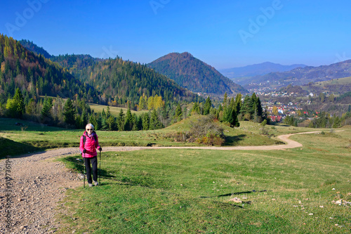 Woman hiking in Pieniny Mountains on a footpath in sunny autumn day, Szczawnica, Poland