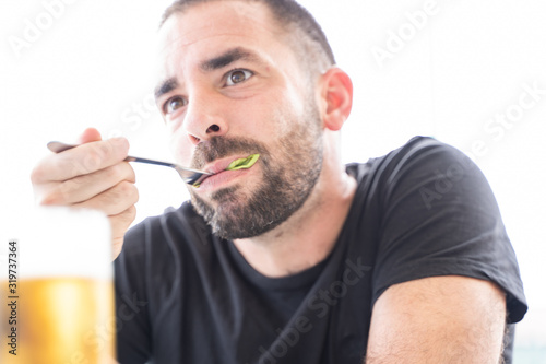 Young man with a beard eating salad