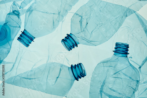 Empty plastic squashed bottles over blue background. Collecting plastic waste to recycling. Concept of plastic pollution and too many plastic waste. Copy space for text. Environmental issue
