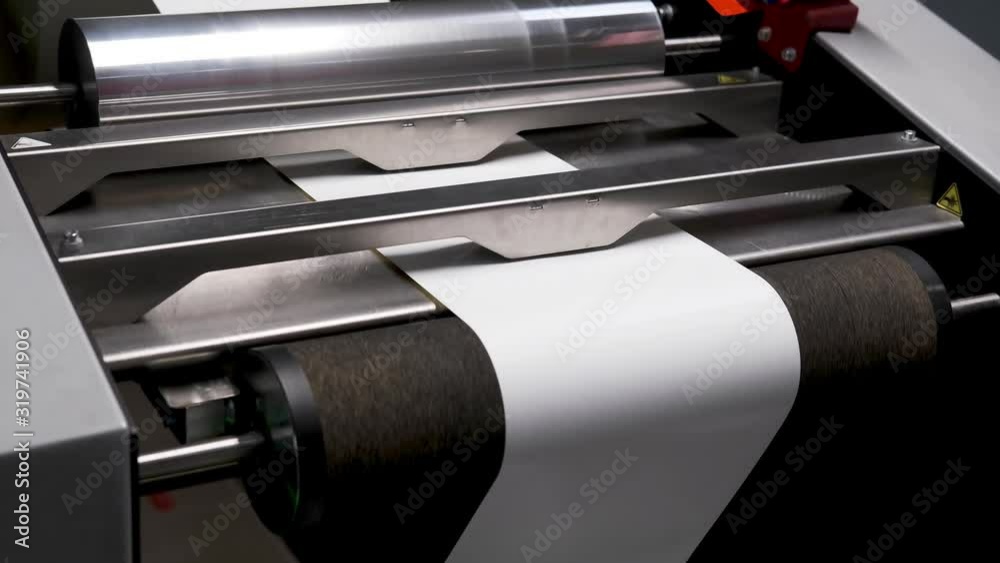 rows of shafts of large offset printing press. moving polymer label ...
