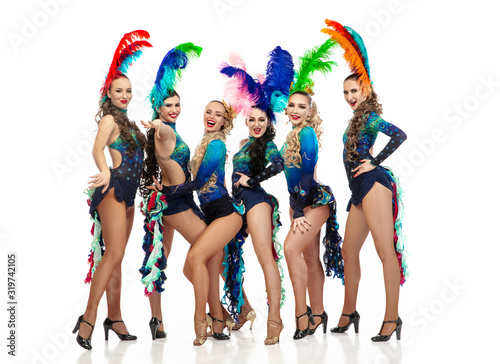 Beautiful young caucasian women in carnival and stylish masquerade costumes with feathers dancing on white studio background. Concept of holidays celebration  festive time  dance  party  having fun.