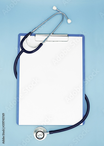 Flat lay of stethoscope and writing pad paper clip board on light blue background with copy space, healthcare and medical concept, top view photo. photo