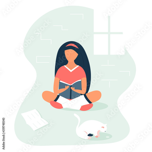 Girl sitting and reading a book in a room.