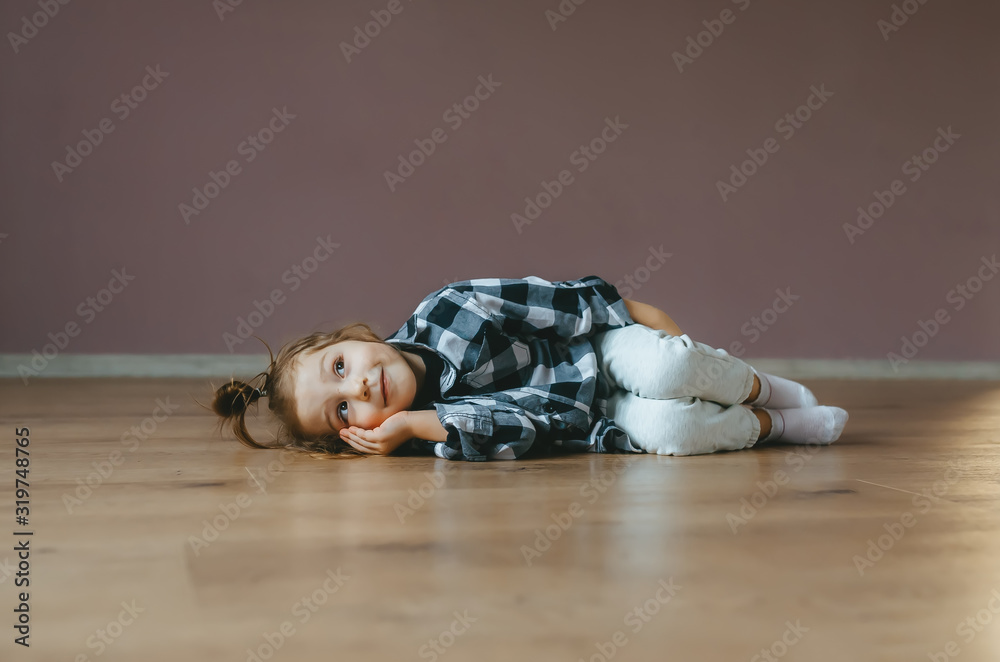 Funny portrait of lying cute little girl on a floor indoors
