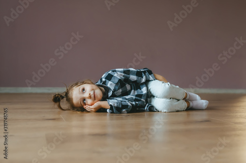 Obraz na płótnie Funny portrait of lying cute little girl on a floor indoors w salonie