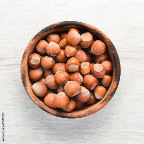 Hazelnuts in bowl on white wooden background. Nut.