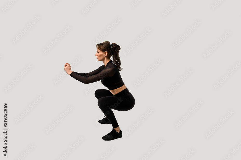 Full length portrait of a young fitness woman doing squatting isolated on a white background