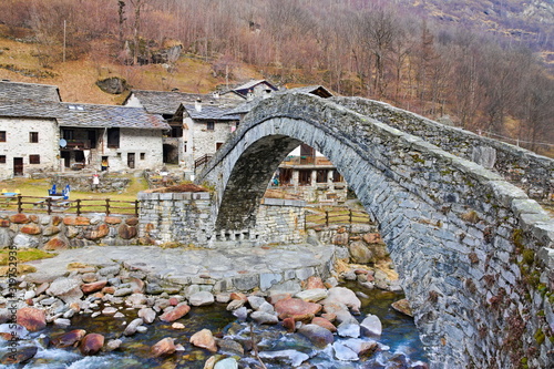 Fondo, Piedmont, Italy - January 20, 2020: Almost abandoned mountain village of Fondo, with an ancient stone bridge over the Chiusella river, on a winter day photo