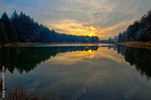 Meugliano lake is a moraine lake of the Ice Age, located in Meugliano, in Valchiusella, Piedmont, Italy. Seen at the sunset of a sunny winter day.