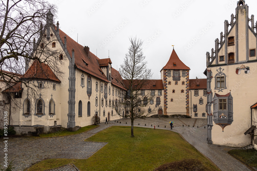 View of the backyard of the Hohes Scloss castle in Fussen on a cloudy winter day, with beautiful painting on facade, Allgaeu, Bavaria, Germany