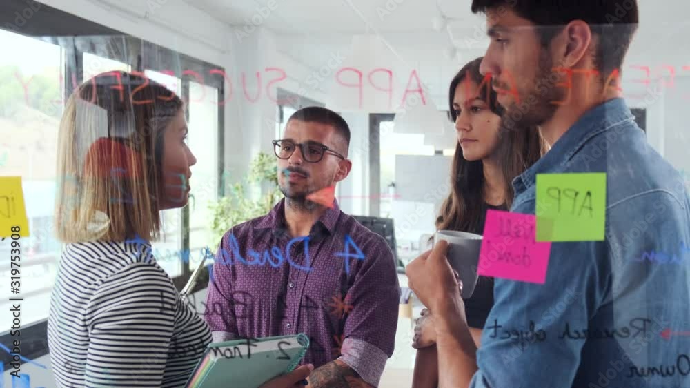 Video of successful business team discussing together in front of office glass board in the coworking space.