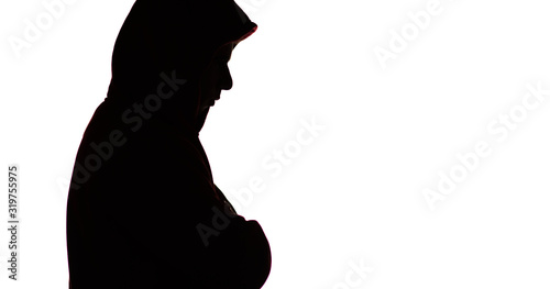 dark male silhouette in casual sportswear with a hood, figure of a guy hiding his face, concept of privacy and confidentiality photo