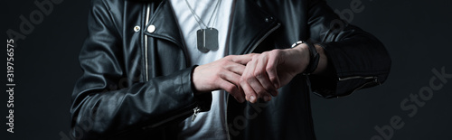cropped view of stylish brutal man in biker jacket with wristwatch isolated on black, panoramic shot photo