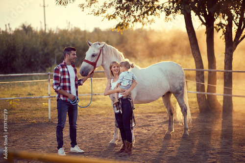 Happy family on the horse ranch .Young happy family having fun at countryside outdoors. Sunset. golden hour