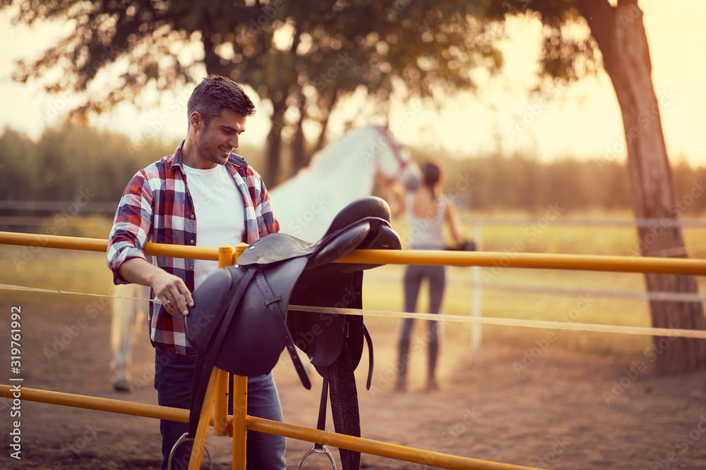 Fotografie Man preparing a horse saddle for a ride