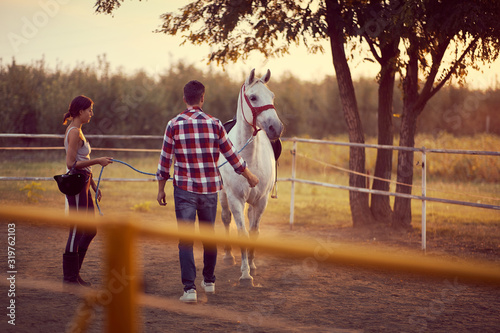 White horse with two people . Training  on countryside, sunset golden hour. Freedom nature concept. photo