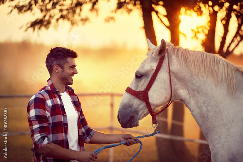 Young man and his horse starting the day together. Fun on countryside, sunset golden hour. Freedom nature concept.
