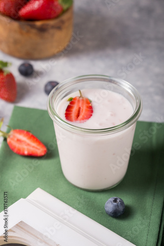 Organic probiotic milk kefir drink or yogurt in glass with strawberry  on the white grey background. Gut health. Fermented dairy beverage. Trendy food. Copy space