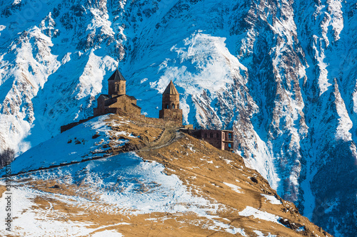 Gergeti Trinity Church in Stepantsminda, Georgia. The temple on the background of the most beautiful mountains of the Caucasus. Winter snow mountain landscape photo