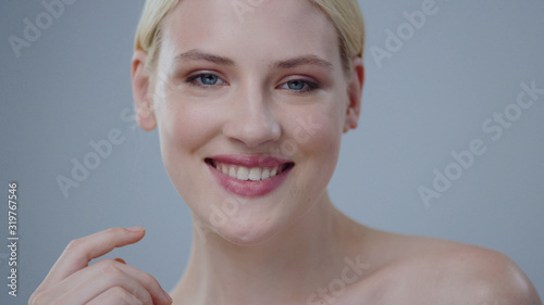 Bilde på lerret Stunning blonde girl with clear angel face smiling charmingly on grey background