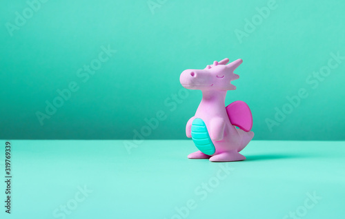 Cute rubber dragon toy on green background.