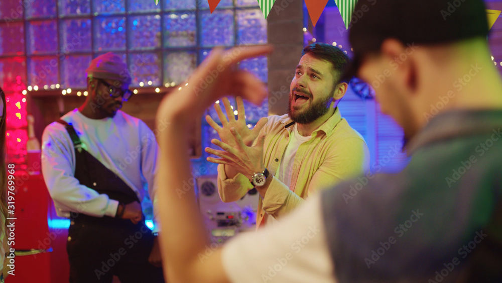 Funny caucasian man dancing in circle of friends making comical gestures and moves hanging out at summer night party. Concept of friendship and fun. Funny caucasian man dancing in circle of friends making comical gestures and moves hanging out at summer night party. Concept of friendship and fun.
