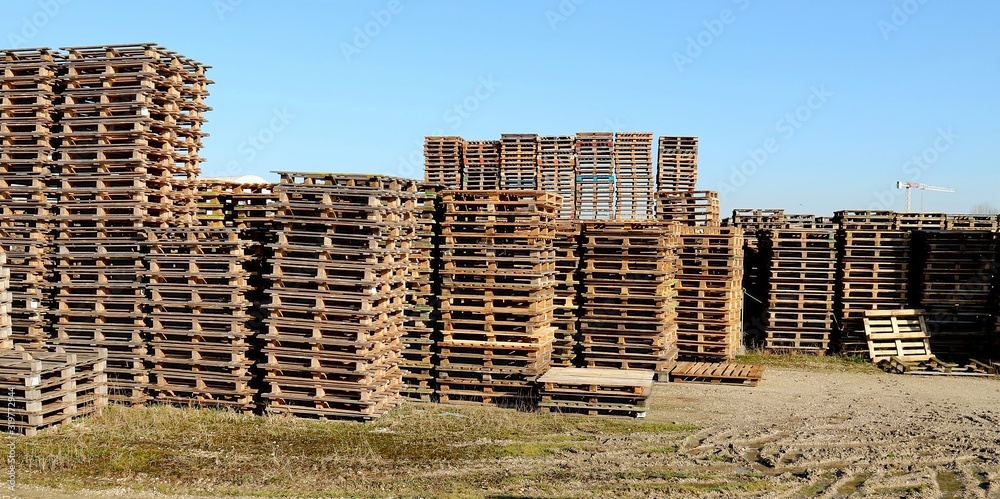 Piles of used wooden pallets in an outdoor storage.