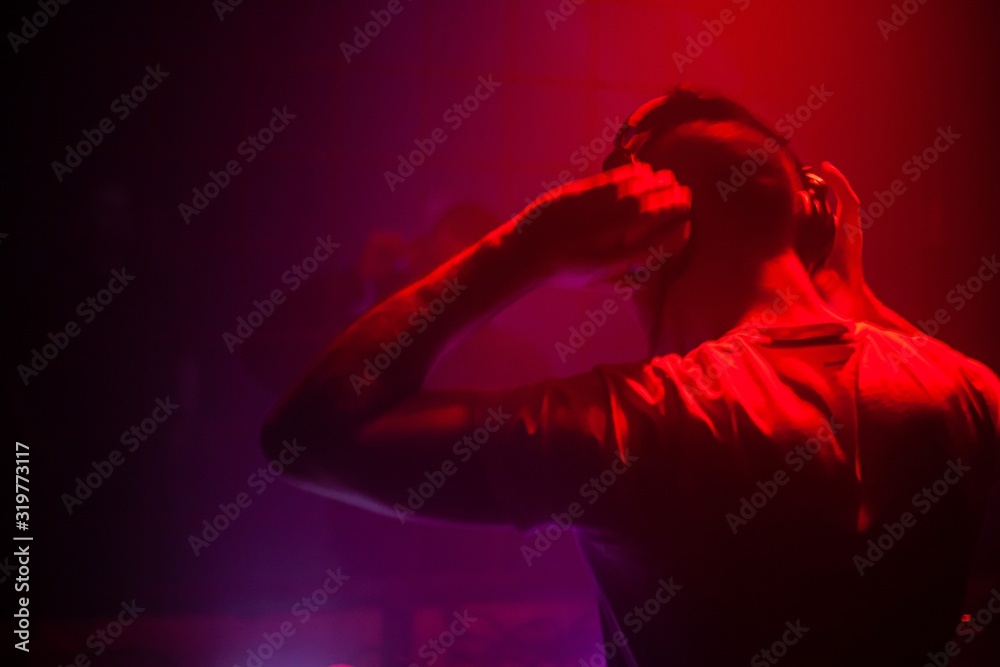 DJ performing electronic music for a live audience in a dark club