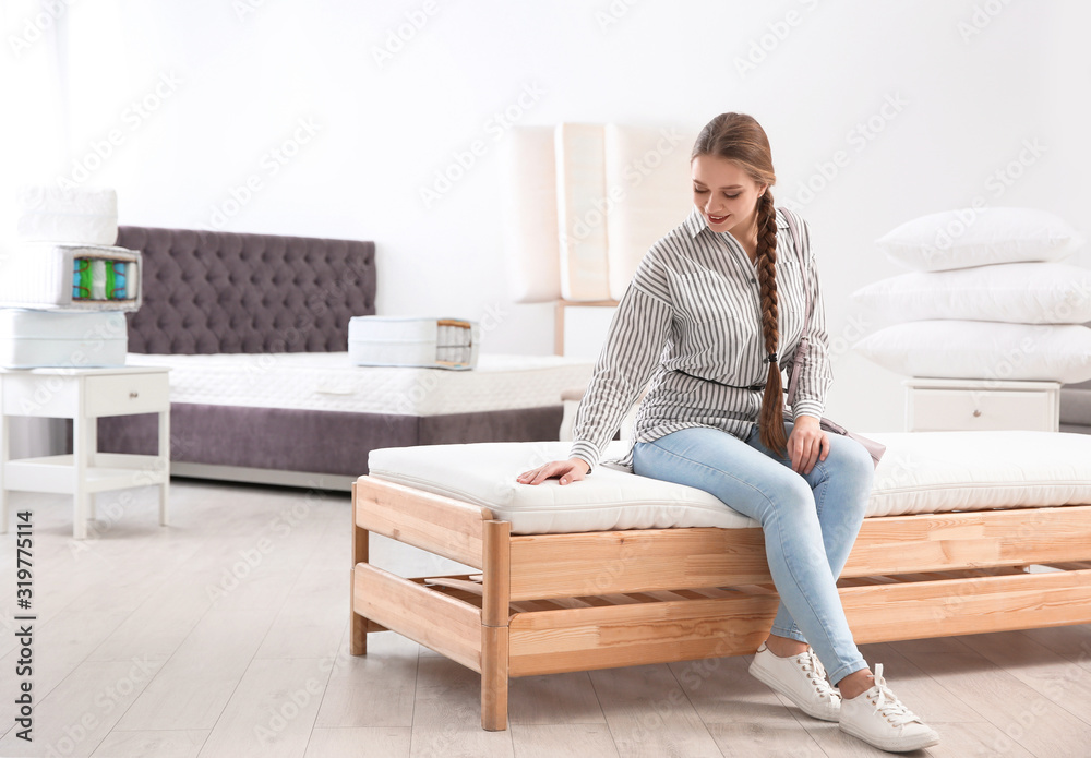 Young woman testing mattress in furniture store. Space for text Young woman testing mattress in furniture store. Space for text