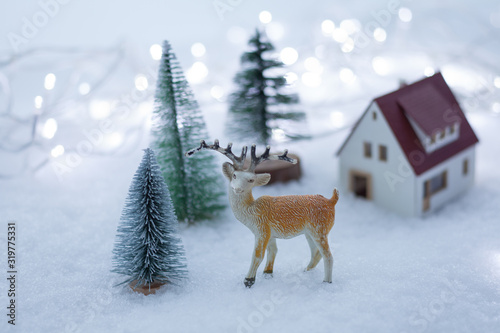 Winter landscape with deer toy, snow, house and fir tree. © oksix