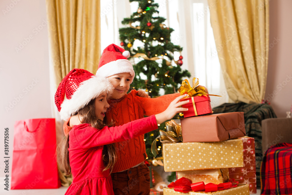 Cheerful cute childrens taking christmas gifts in the room