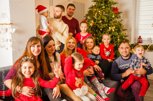 Large family posing on sofa near Christmas tree