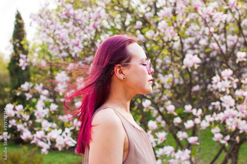 Creative young woman with pink hair dreams with closed eyes