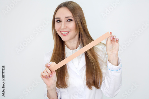 Tableau sur toile The girl shows how to do face taping, in a white coat on a white background and smiles